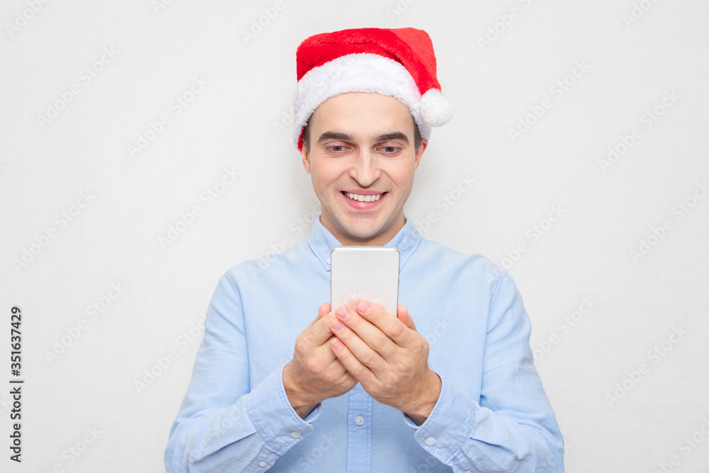 Concept of a new year. Happy man in Santa Claus hat with phone, portrait, white background Concept of a new year. Happy man in Santa Claus hat with phone, portrait, white background