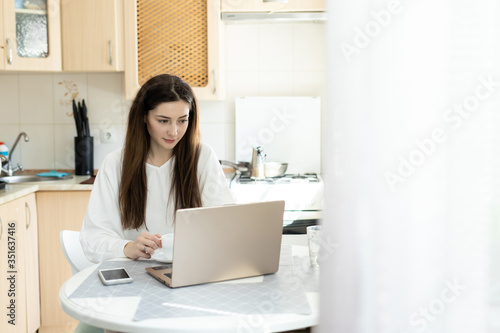 The girl studing online with laptop in kitchen