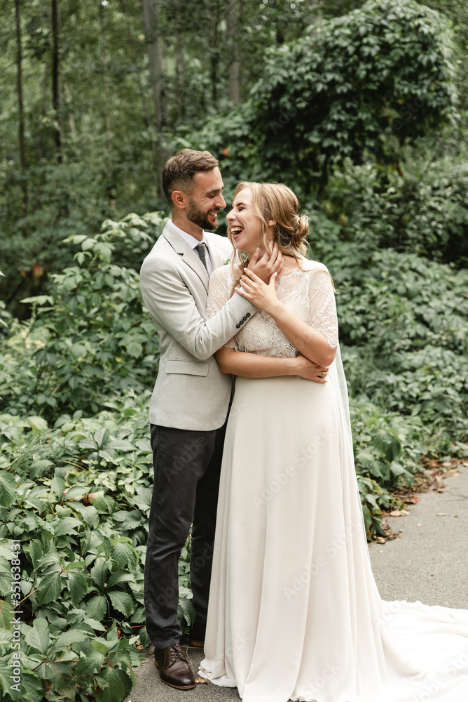 holiday newlyweds,tender hugs of a young couple,the groom touches the face of the bride,cheerful and joyful wedding couple walks in the park holiday newlyweds,tender hugs of a young couple,the groom touches the face of the bride,cheerful and joyful wedding couple walks in the park