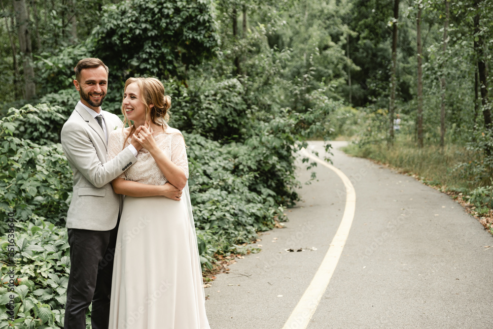 portrait of a happy wedding couple on their wedding day,beautifully dressed newlyweds tenderly hug while walking in a park,handsome bearded groom gently hugs his bride portrait of a happy wedding couple on their wedding day,beautifully dressed newlyweds tenderly hug while walking in a park,handsome bearded groom gently hugs his bride