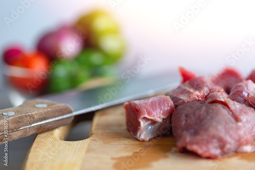 Close up of meat cut into beef stew cubes chunks on wooden board. Cooking dinner on kitchen table concept