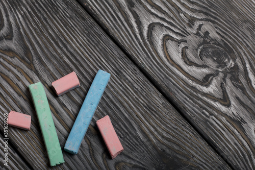 Pieces of chalk for drawing  different colors. They lie on pine boards painted with white and black paint.
