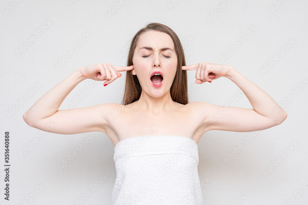 Unhappy young woman screaming and covers her ears, ignore the unpleasant sound, white background, copy space Unhappy young woman screaming and covers her ears, ignore the unpleasant sound, white background, copy space