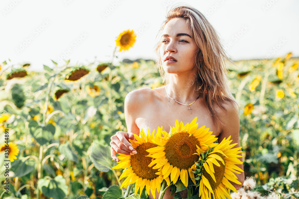 A young topless girl stands in sunflowers A young topless girl stands in sunflowers