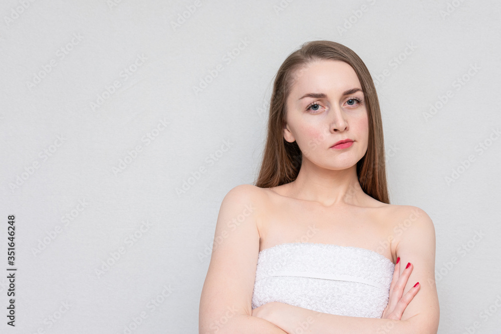 Upset naked woman in a towel, girl looking at camera, white background, copy space Upset naked woman in a towel, girl looking at camera, white background, copy space