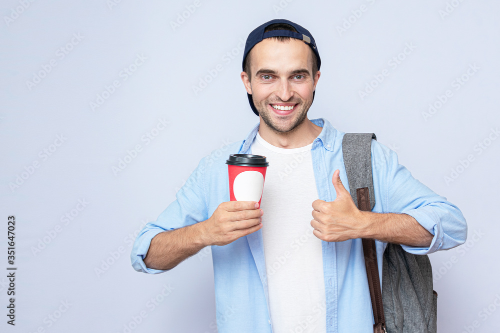 Man with a Cup of coffee shows a super hand sign. Gray background, portrait Man with a Cup of coffee shows a super hand sign. Gray background, portrait