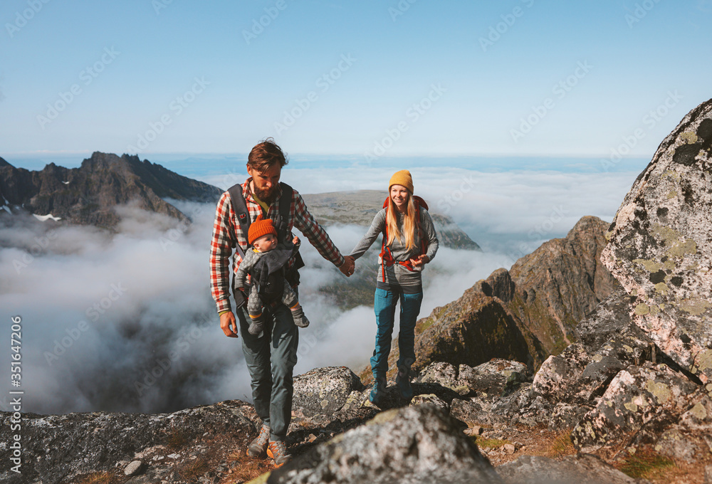 Family travel vacations man and woman hiking with baby carrier outdoor in mountains healthy lifestyle mother and father walking holding hands summer trip in Norway Stock Foto Adobe Stock