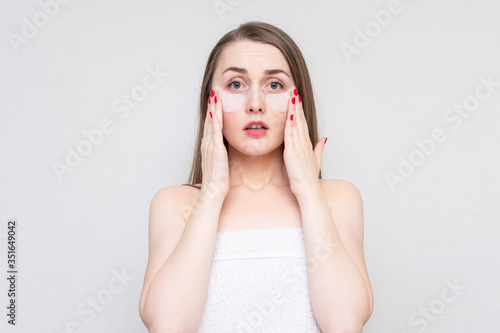 Wallpaper Mural Upset woman using white under eye patches, white background. Concept of eye skin treatment Torontodigital.ca