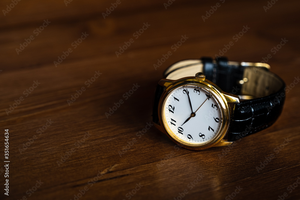 Retro golden wristwatch with Roman numerals on the dial lie on a wood. Retro golden wristwatch with Roman numerals on the dial lie on a wood.