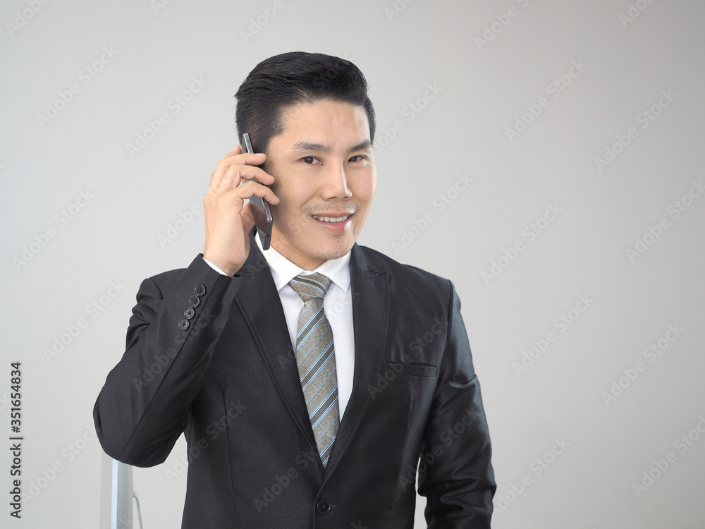 Handsome asian businessman in suit talking on mobile phone in modern office. Handsome asian businessman in suit talking on mobile phone in modern office.