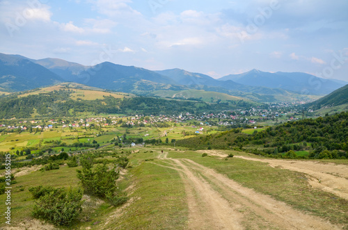 Beautiful sky and forest high up in Carpathians. Summer mountains landscape and small village. Carpathian, Ukraine