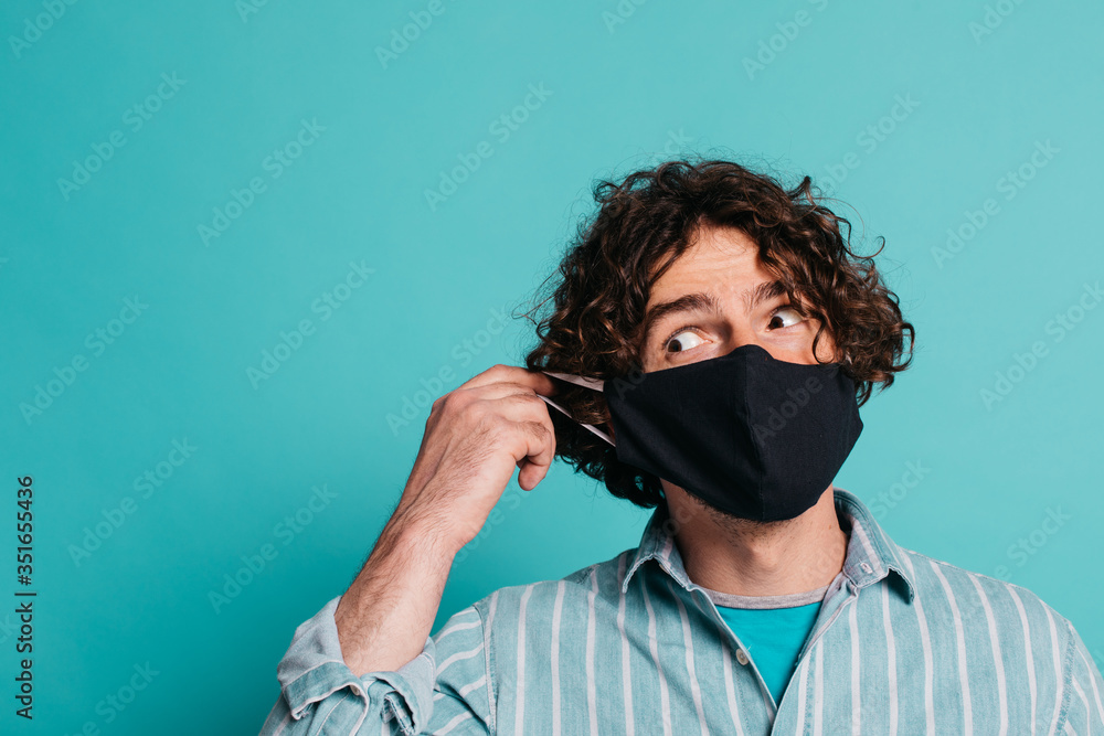 Funny male putting corona COVID-19 and SARS mask on face and looking sideways. Funny male putting corona COVID-19 and SARS mask on face and looking sideways.