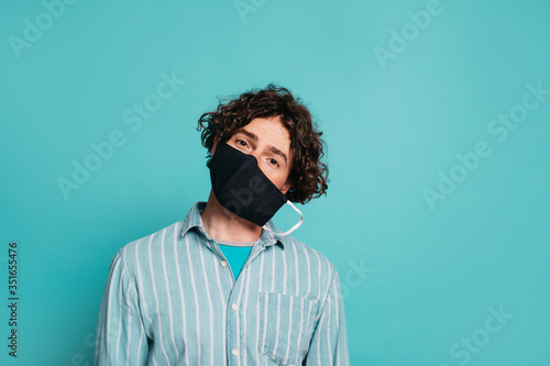 Attractive man in blue shirt wearing medical mask to protect from corona COVID19