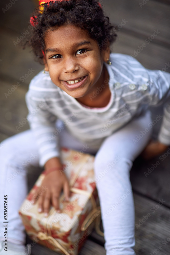 Kids birthday party . Little afro-american girl in birthday cap holding birthday presents. Kids birthday party . Little afro-american girl in birthday cap holding birthday presents.