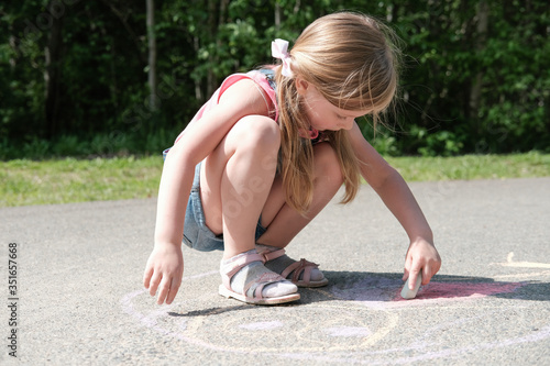 little girl playing with a sand and building sandcastle. cute little girl spending time on sea coast. blonde caucasian child. life after quarantine. outdoors children activity.