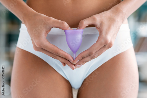 Young woman hands holding menstrual cup on the bathroom. photo