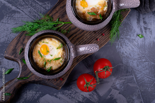 Soup with poached egg in cocotte on the wooden board photo