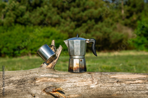 Metal cup and coffee maker in nature. Making coffee. Camping in summer.