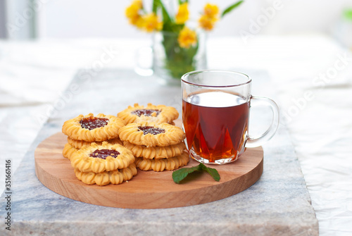 Tasty hot black tea. Homemade fresh cookies and a cup of tea on marble table on white light grey background.