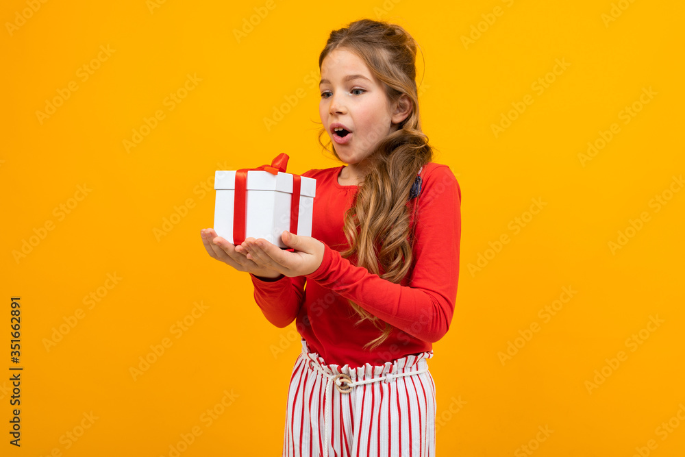 surprised girl with a gift box on a yellow background surprised girl with a gift box on a yellow background