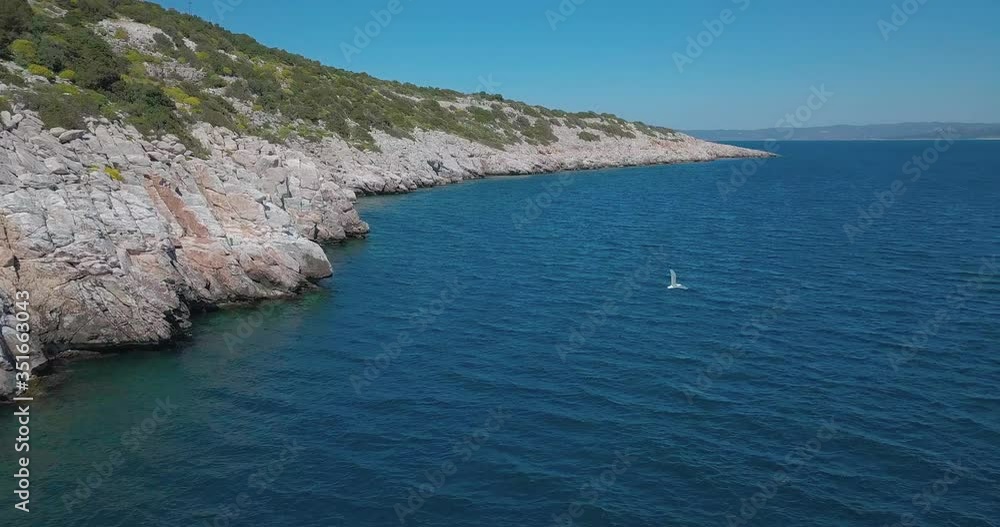 Forward drone shot next to a rocky shore in the aegean sea crossing paths with a seagull. Shot in 4K Forward drone shot next to a rocky shore in the aegean sea crossing paths with a seagull. Shot in 4K