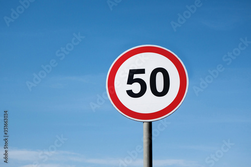 International traffic sign 'Speed limit' (to 50 km or miles per hour). Clear blue sky is on  background