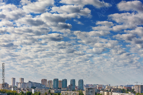 Small white-gray clouds gradually obscure the blue sky above the city.