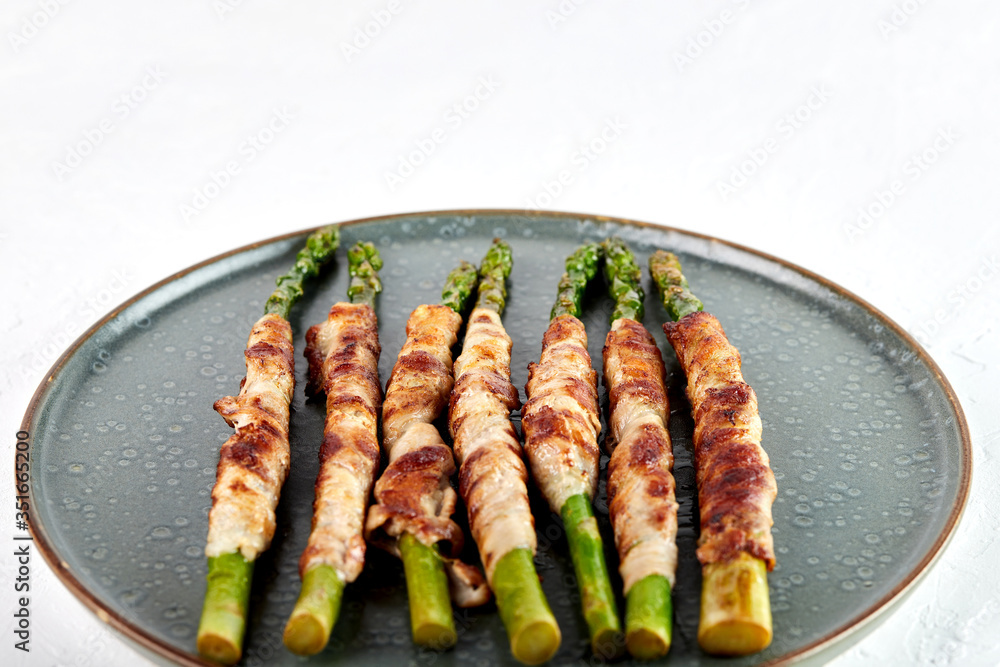 Fresh Organic Asparagus baked with bacon in the oven, close-up, top view Fresh Organic Asparagus baked with bacon in the oven, close-up, top view