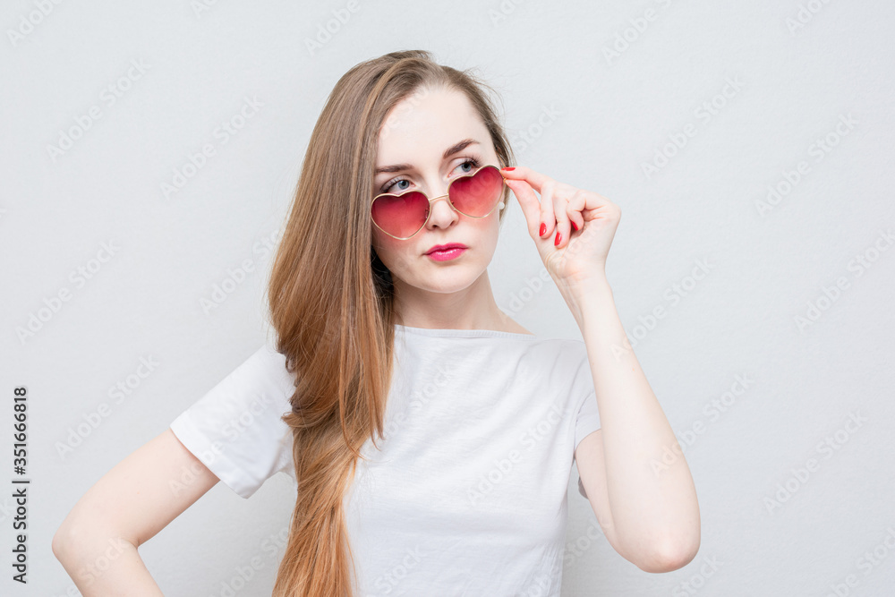 Fatal woman takes off her heart-shaped glasses and looks at someone in the side, portrait, white background Fatal woman takes off her heart-shaped glasses and looks at someone in the side, portrait, white background
