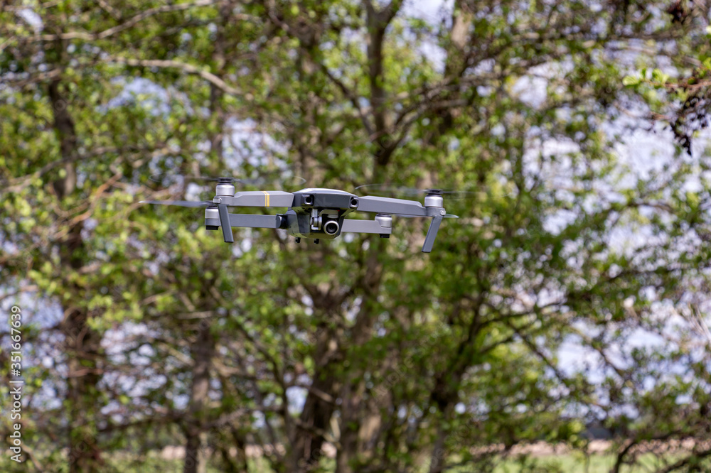 A small drone flies in the forest.