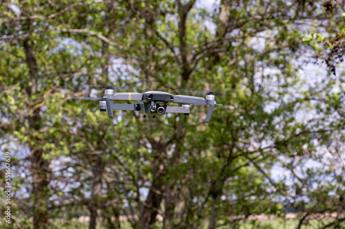 A small drone flies in the forest.