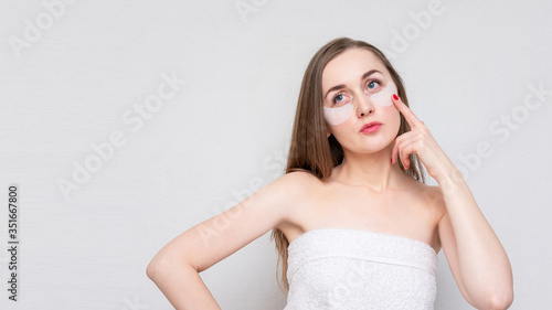 Young woman with eye patches, white background, copy space. Concept of eye skin treatment, 16:9