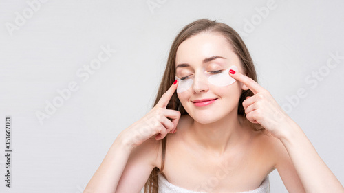 Woman shows eye patches, white background, white background, copy space, 16:9. Concept of beauty