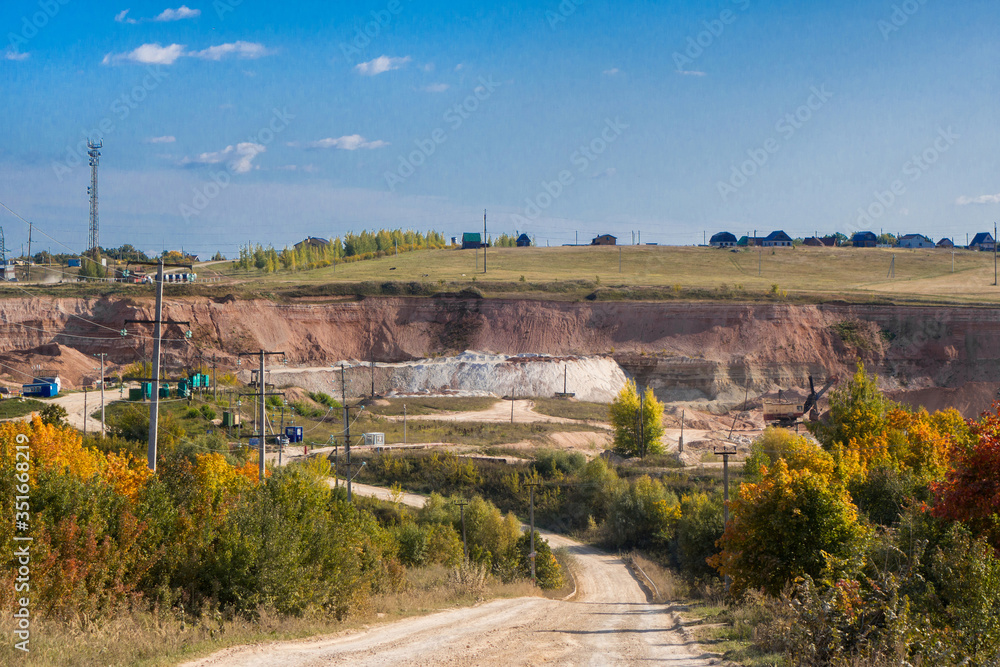 Panoramic view onto entrance of quarry, where's mining limestone, sandstone, clay & other earth resources. There are high voltage power lines, quarry excavator, parts of crushing plant, stockpiles etc