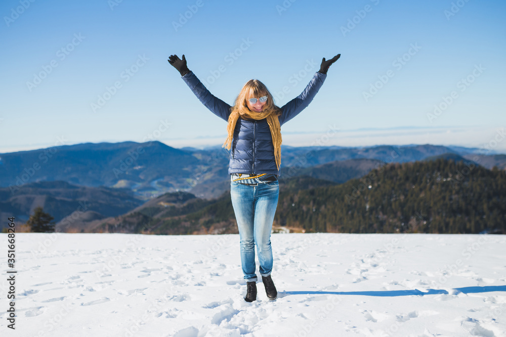 After the pandemic cheerful happy woman raises her hands under the snow in winter on a mountain road After the pandemic cheerful happy woman raises her hands under the snow in winter on a mountain road
