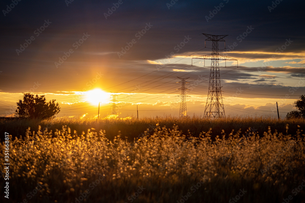 sunset landscape with high voltage electricity pylons