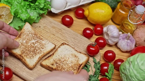 Add garlic in mashed avocado and mix in a glass bowl. Cooking a delicious healthy vegetarian breakfast. View of a healthy breakfast with a variety of fresh products on the table. Avocado Sandwich.
