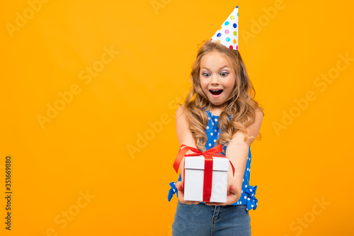 Nice little girl with a birthday party holds a present isolated on white background