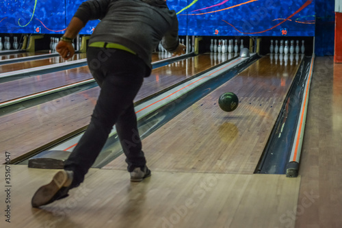 Man playing bowling seen from the back, focus on the ball.