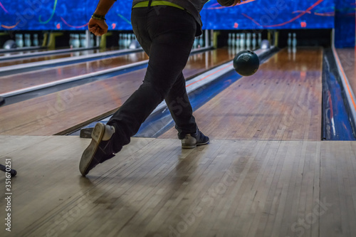 Man playing bowling seen from the back, focus on the ball.