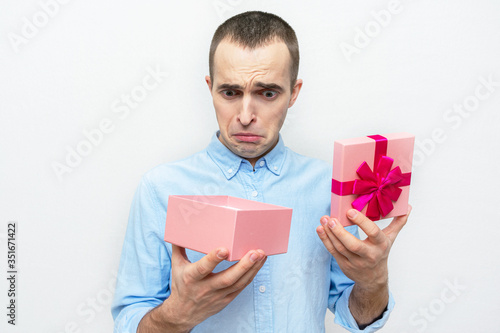 Upset man with opened gift box, white background, concept of bad gifts for holidays