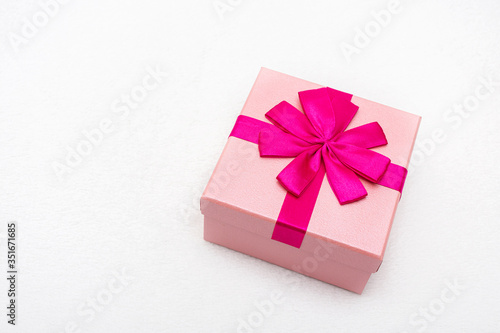Gift with pink ribbon for Valentine's Day, white background, closeup, copy space, top view