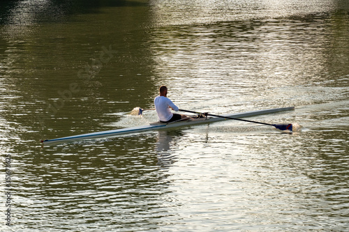 A young male athlete is rowing in a single scull on the Danube, Budapest Hungary