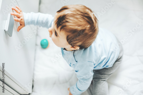 Baby boy touching door in the kitchen