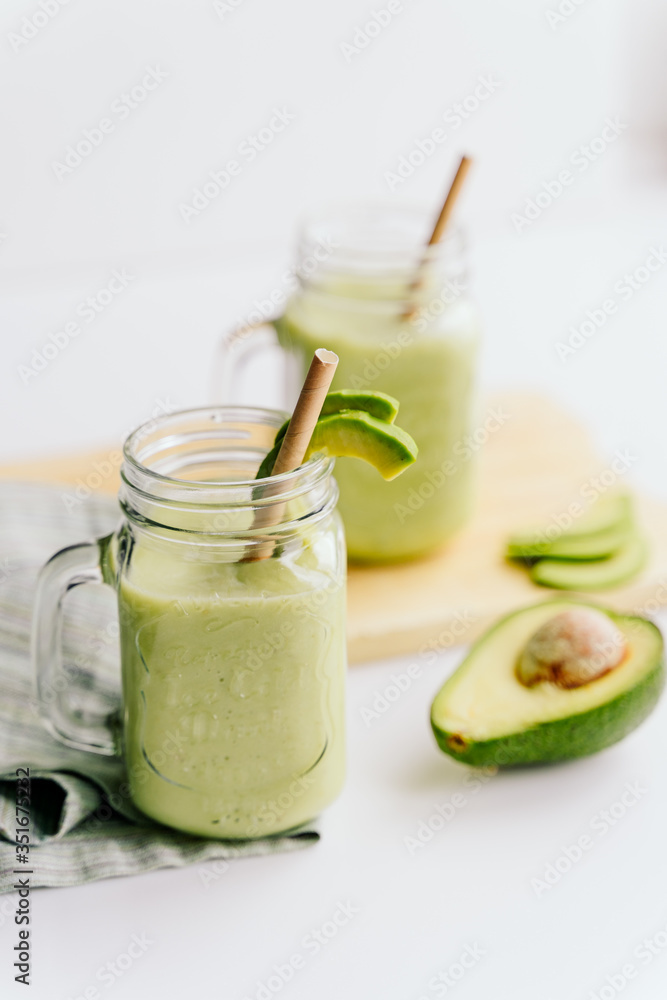 creamy smoothie from avocado and banana in glass cups with paper tubes on a light background. no plastic. healthy food creamy smoothie from avocado and banana in glass cups with paper tubes on a light background. no plastic. healthy food