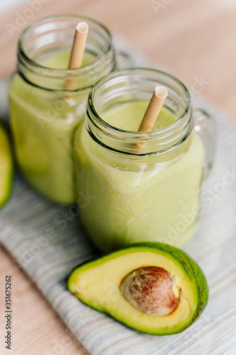 creamy smoothie from avocado and banana in glass cups with paper tubes on a light background. no plastic. healthy food