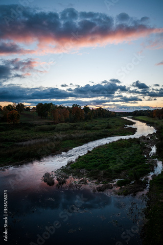 Slow river with dramatic clouds and trees around