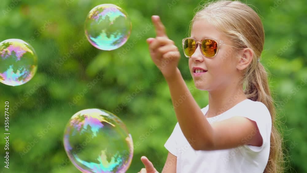 Nine-year-old girl plays with soap bubbles in the summer garden. Nine-year-old girl plays with soap bubbles in the summer garden.