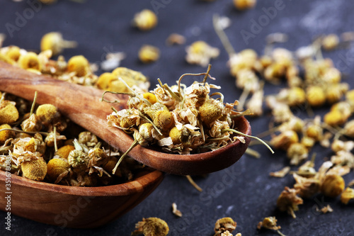 Heap of dried chamomile lying on rustic surface. healthy nutrition concept, herbalism and alternative medicine with chamomile photo