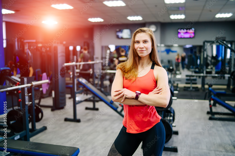 Fototapeta premium Strong sexy blonde woman with fitness muscular body posing near equipment in gym. Concept of sports healthy habits. Showing biceps.
